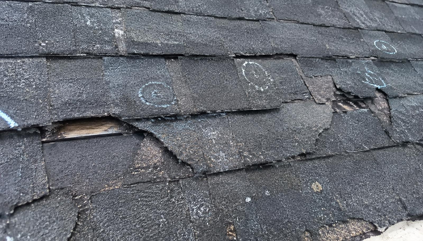 Close-up of hail damaged asphalt roof shingles marked during inspection